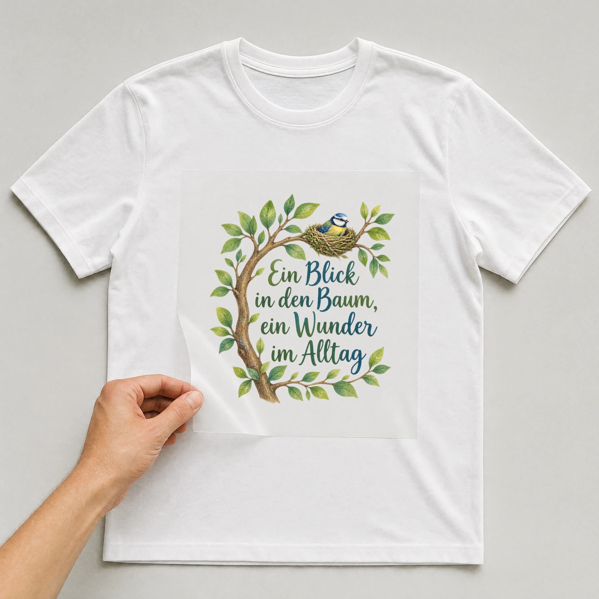 Bügelbild „Ein Blick in den Baum, ein Wunder im Alltag“ auf weißem T-Shirt, Folie wird aufgelegt
