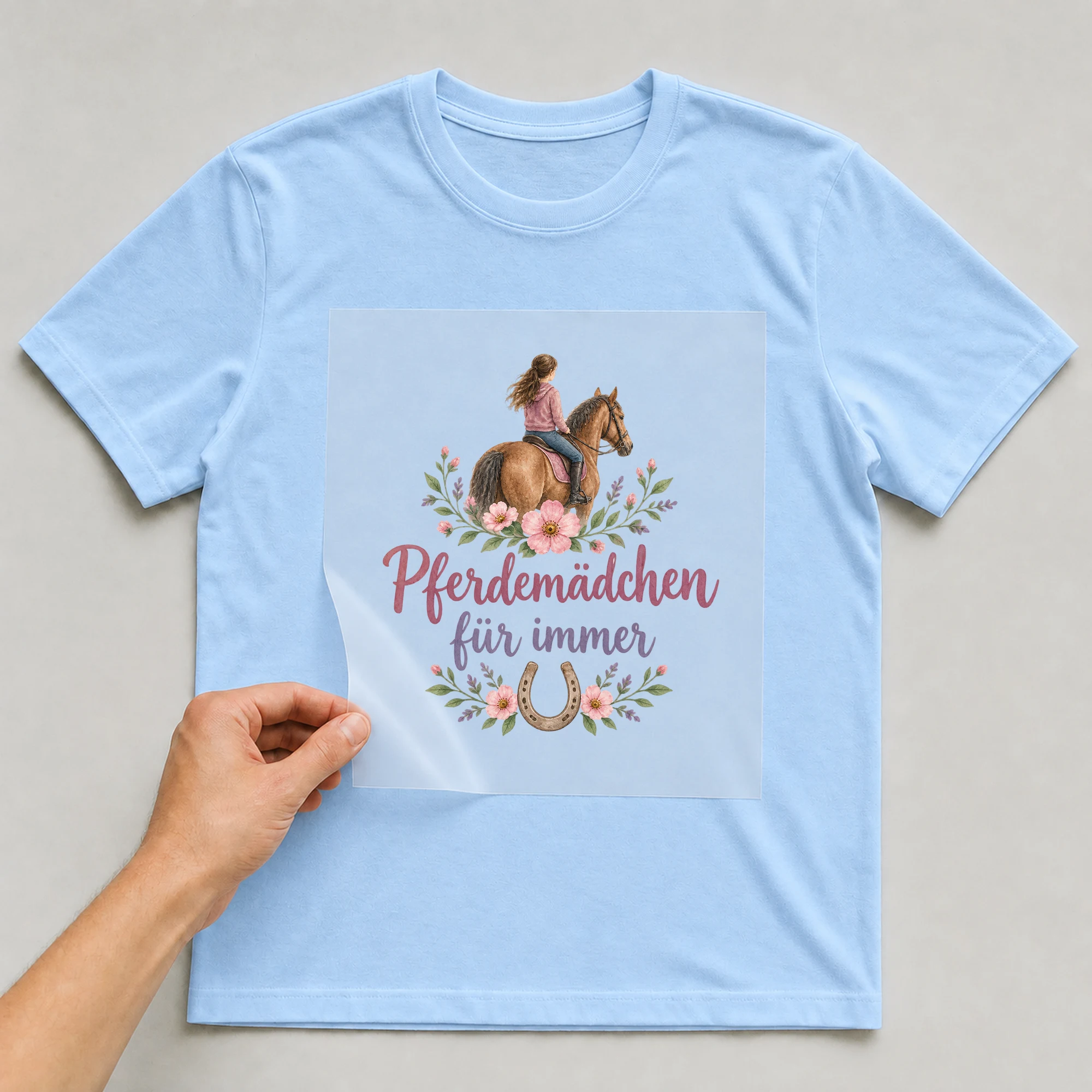 Bügelbild „Pferdemädchen für immer“ auf babyblauem T-Shirt, Folie wird aufgelegt