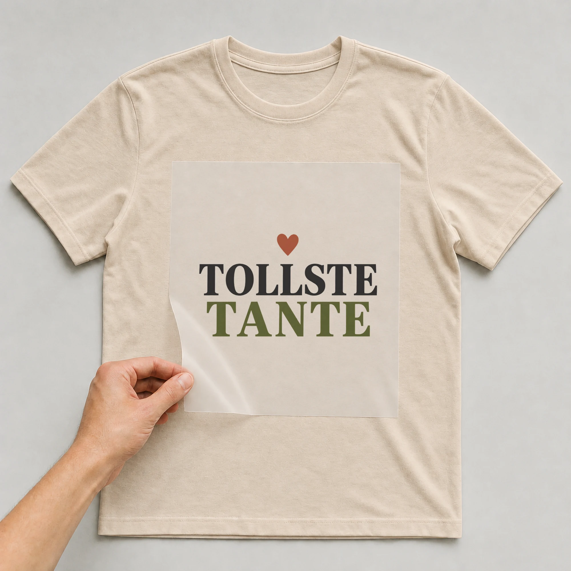 Bügelbild „Tollste Tante“ auf beigem T-Shirt, Folie wird aufgelegt