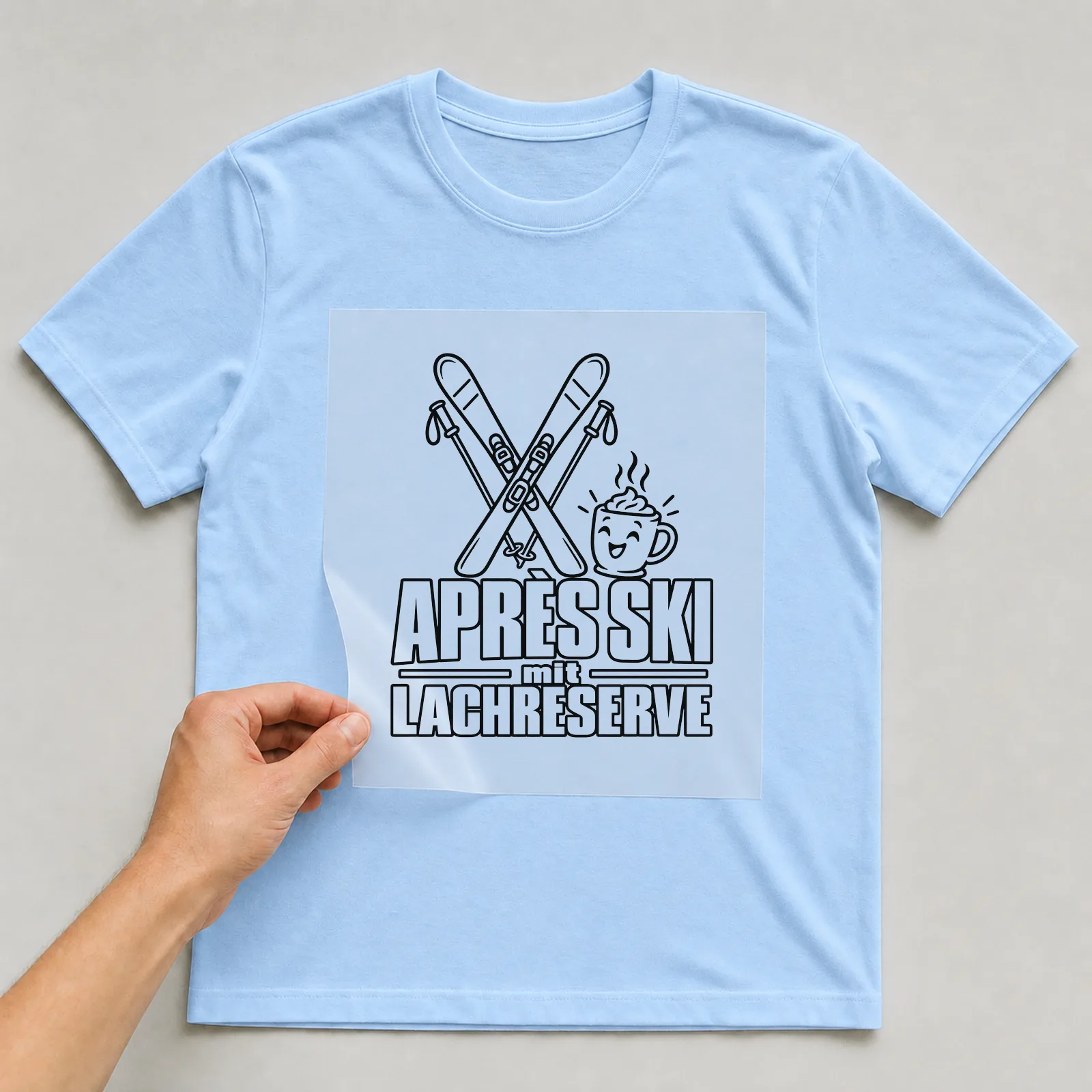 Bügelbild „Après Ski mit Lachreserve“ auf hellblauem T-Shirt, Folie wird aufgelegt