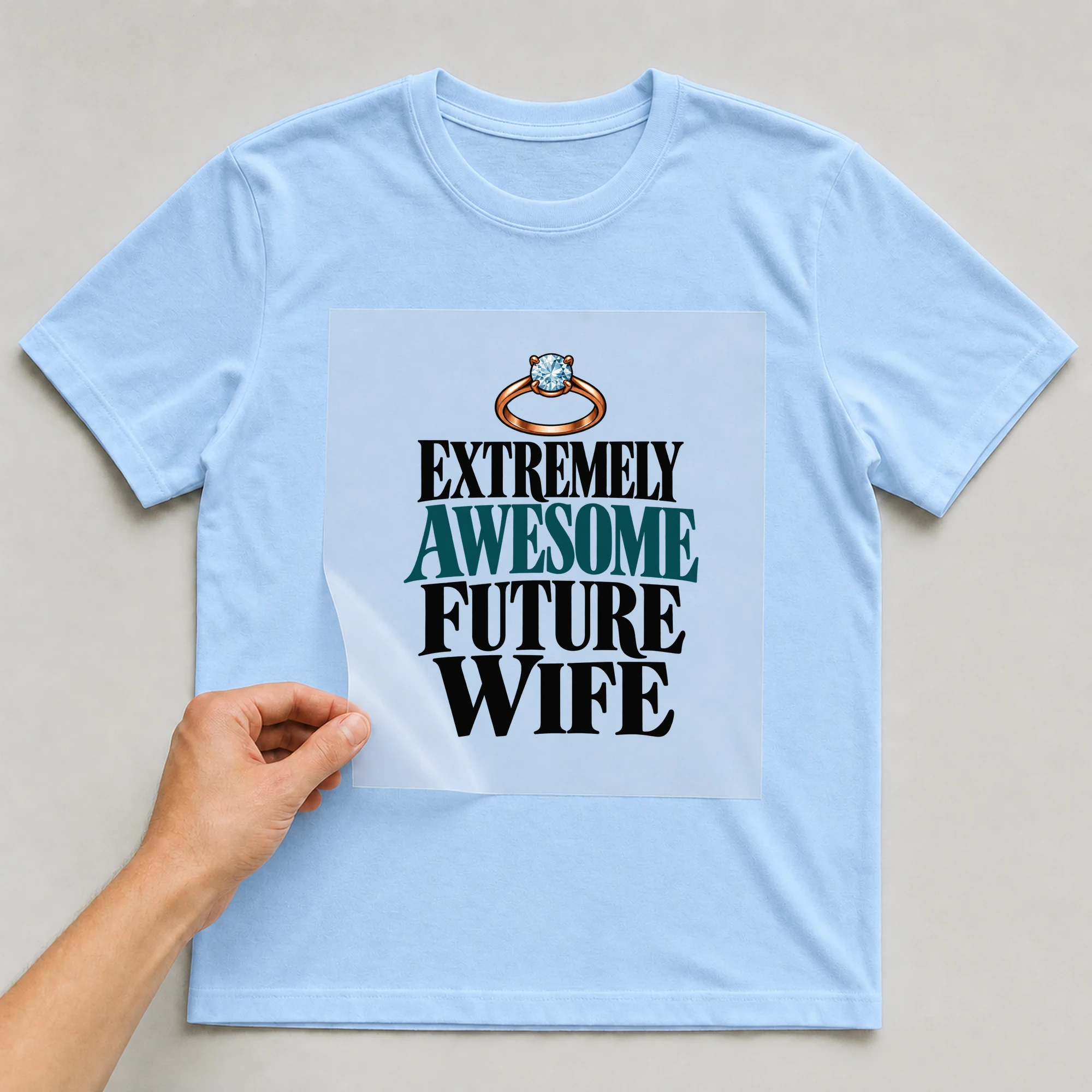 Bügelbild „Extremely Awesome Future Wife“ auf babyblauem T-Shirt, Folie wird aufgelegt