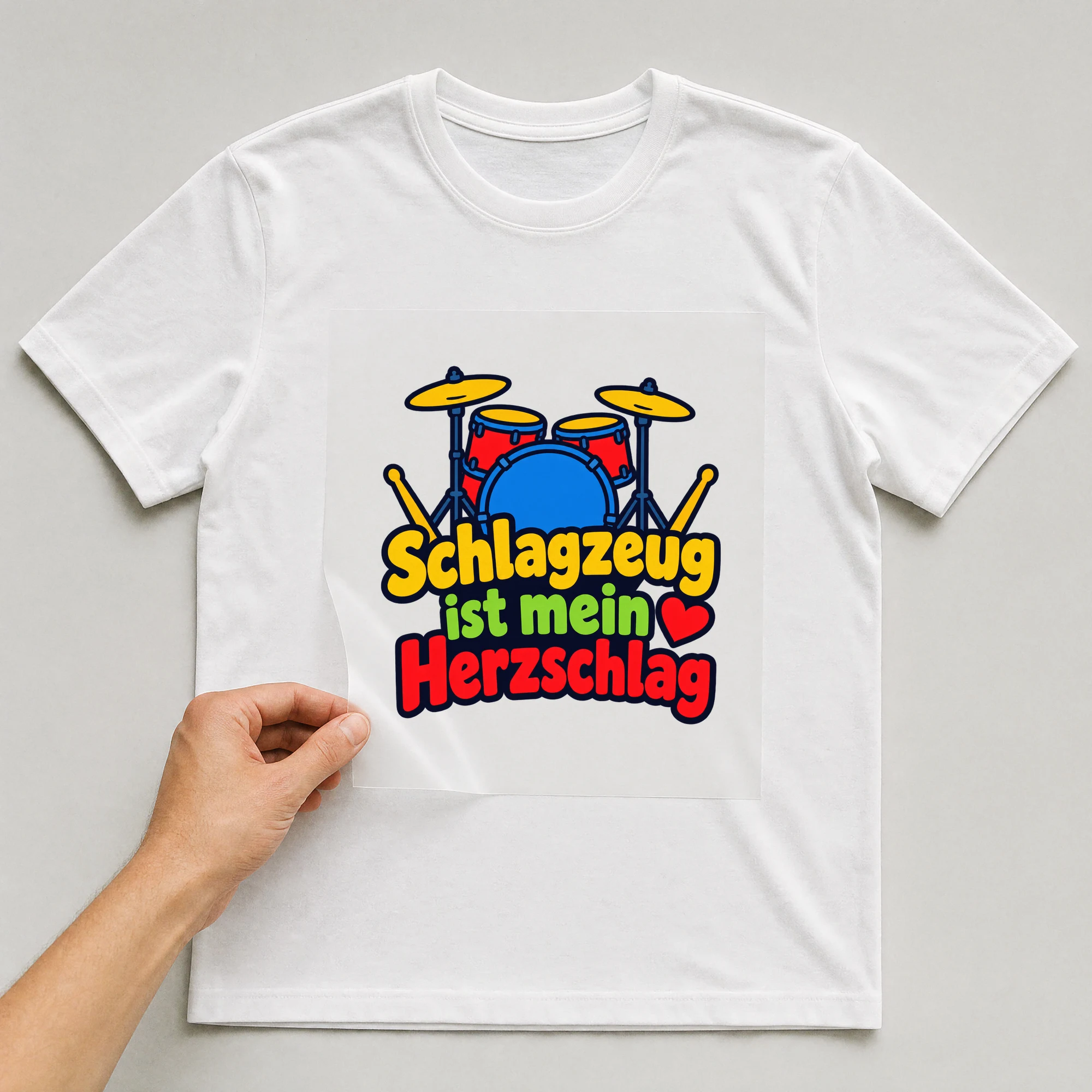 Bügelbild „Schlagzeug ist mein Herzschlag“ auf weißem T-Shirt, Folie wird aufgelegt