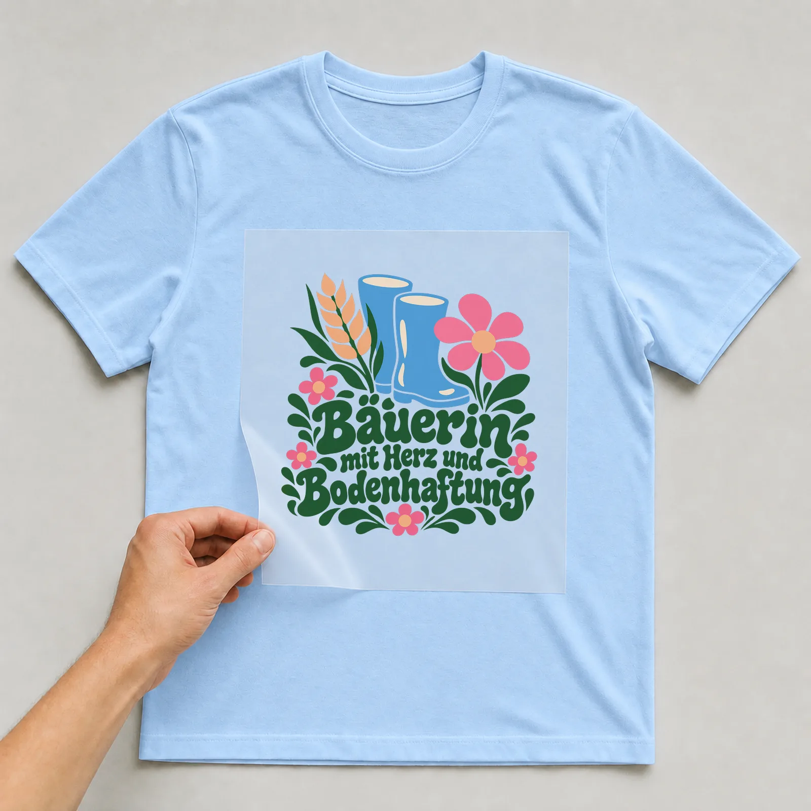 Bügelbild „Bäuerin mit Herz und Bodenhaftung“ auf hellblauem T-Shirt, Folie wird aufgelegt