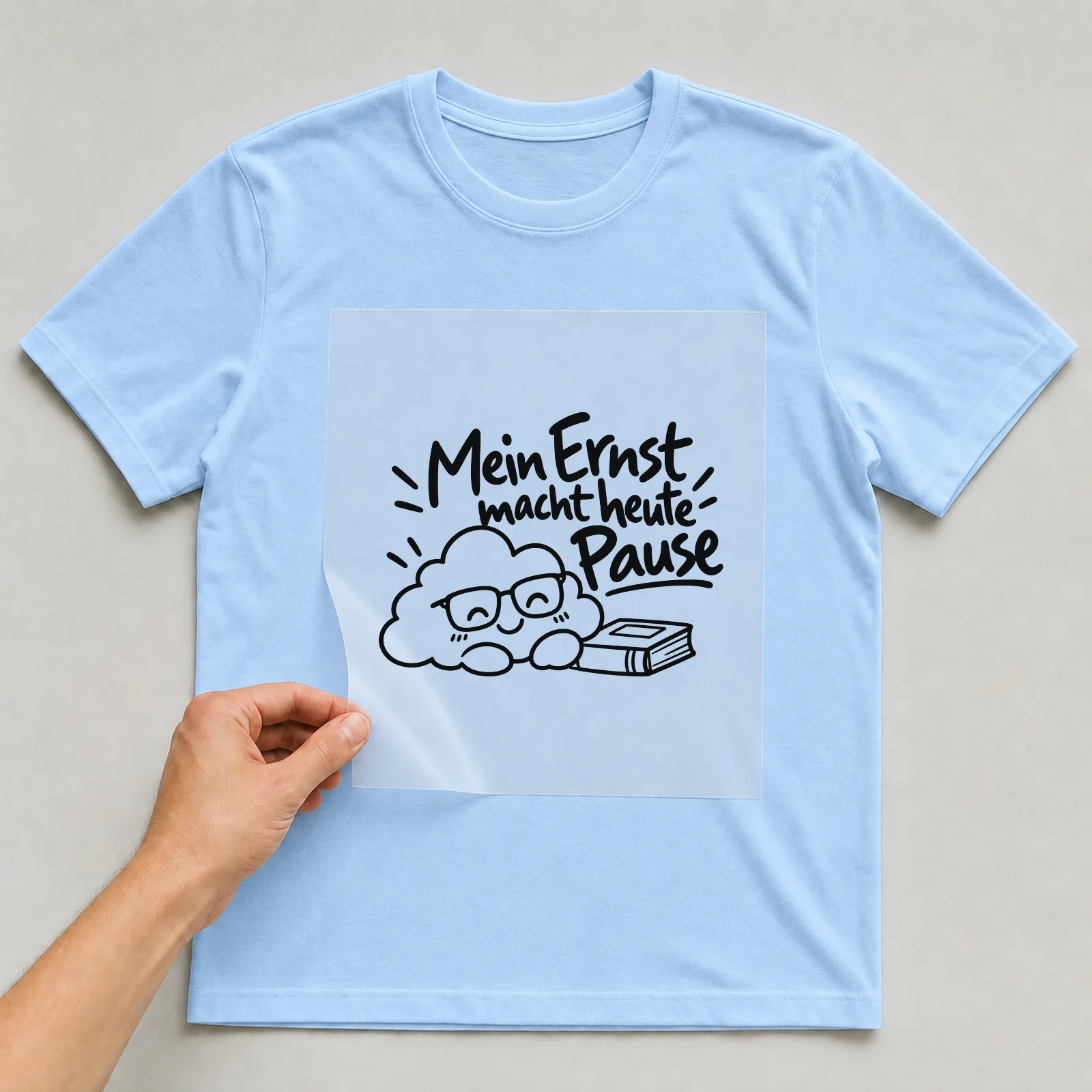 Bügelbild „Mein Ernst macht heute Pause“ auf hellblauem T-Shirt, Folie wird aufgelegt