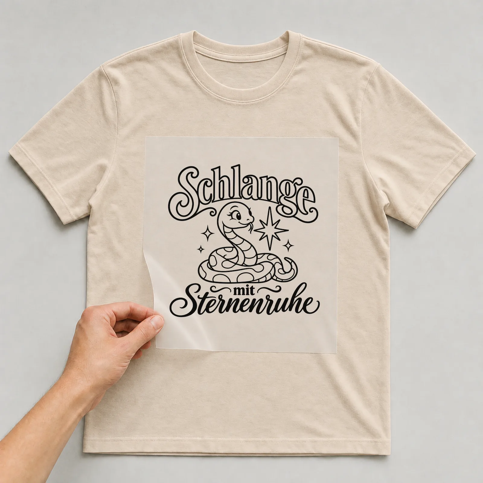Bügelbild „Schlange mit Sternenruhe“ auf beigem T-Shirt, Folie wird aufgelegt