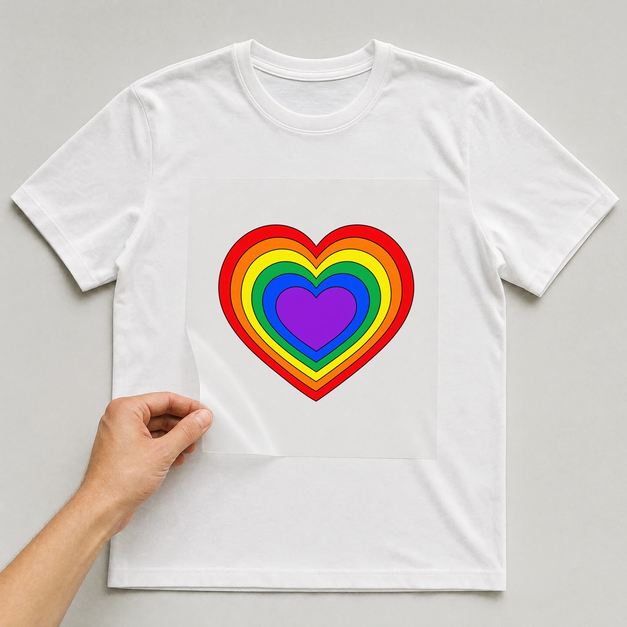 Bügelbild „Love Rainbow Heart“ auf weißem T-Shirt, Folie wird aufgelegt