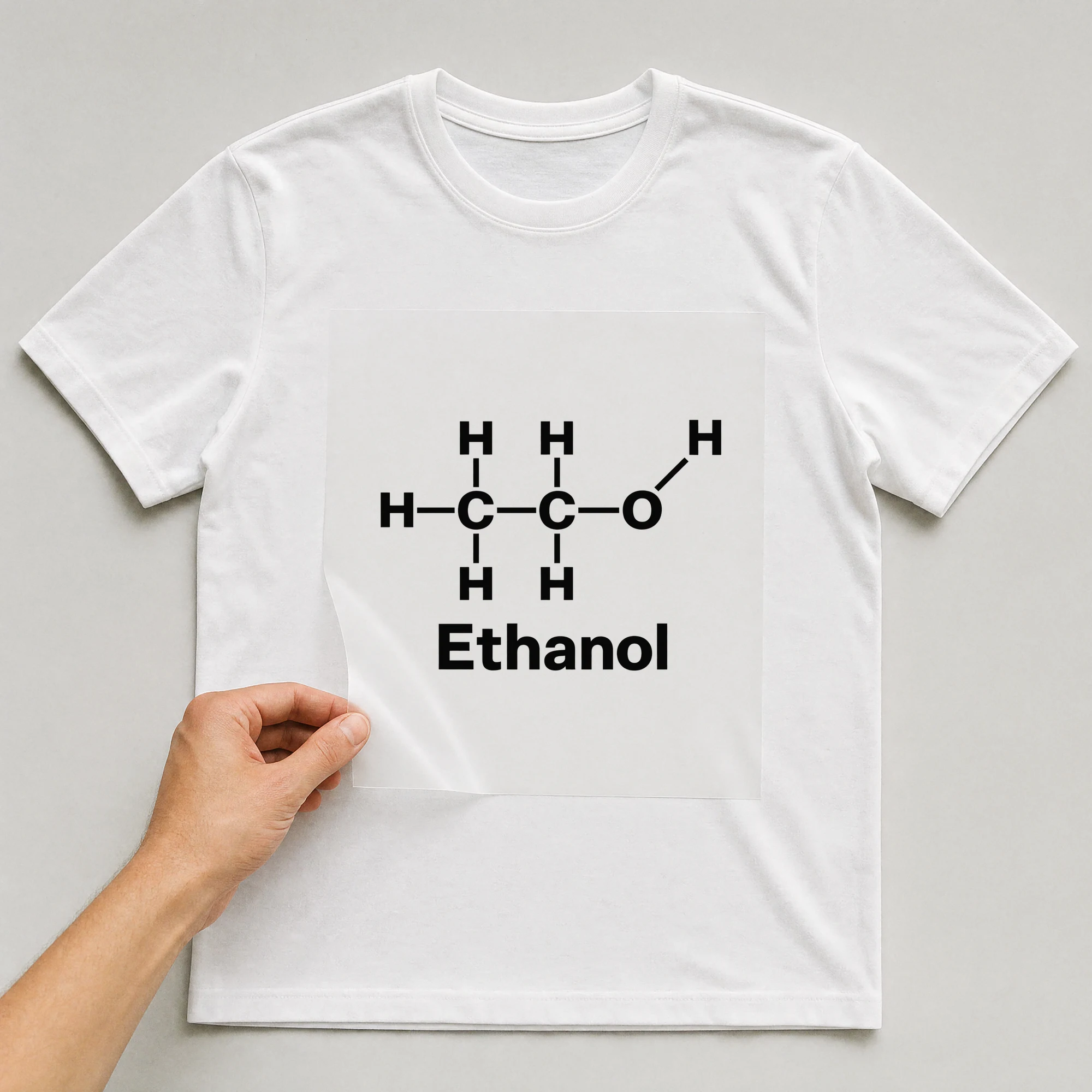 Bügelbild „H H H H C C O H H Ethanol“ auf weißem T-Shirt, Folie wird aufgelegt