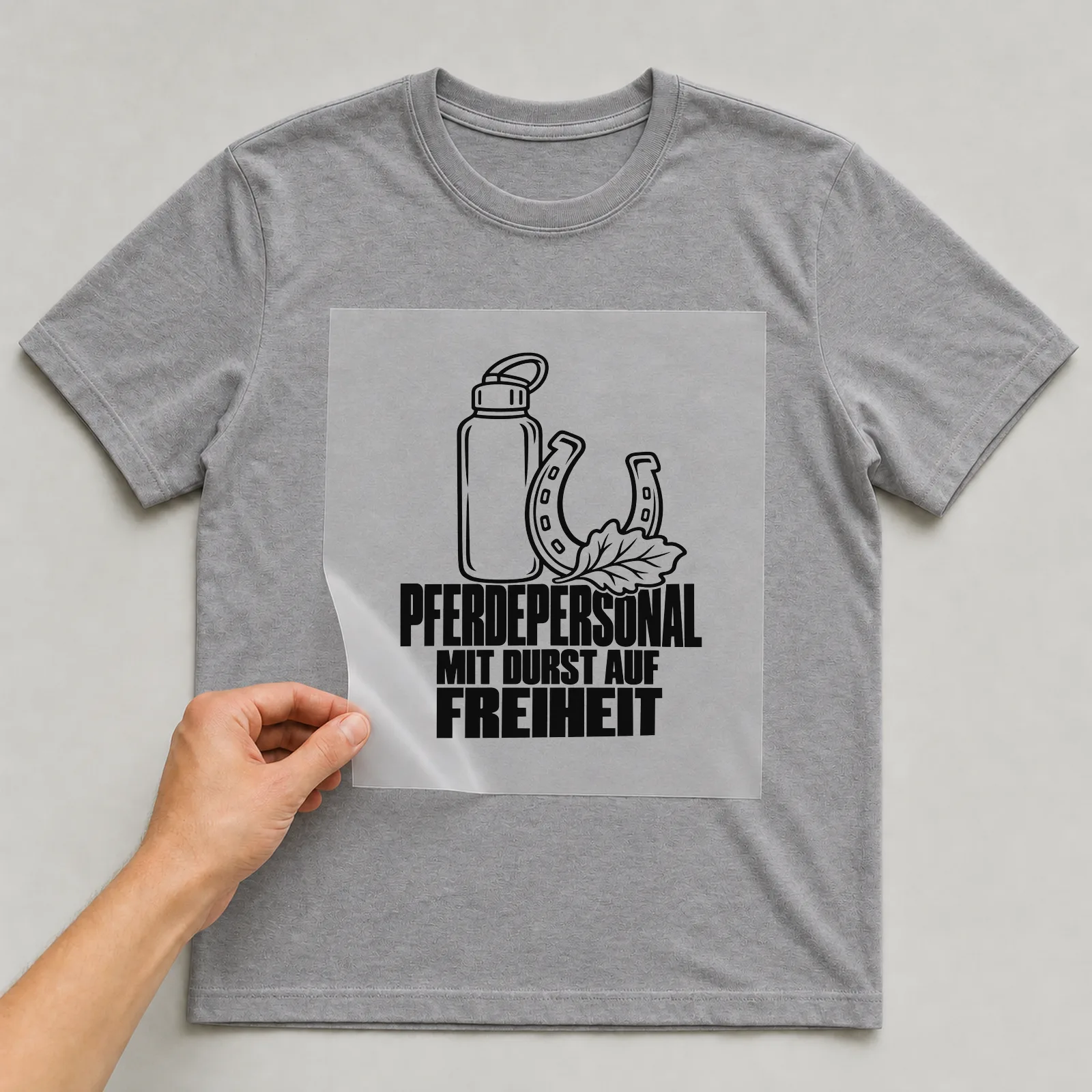 Bügelbild „Pferdepersonal mit Durst auf Freiheit“ auf grauem T-Shirt, Folie wird aufgelegt