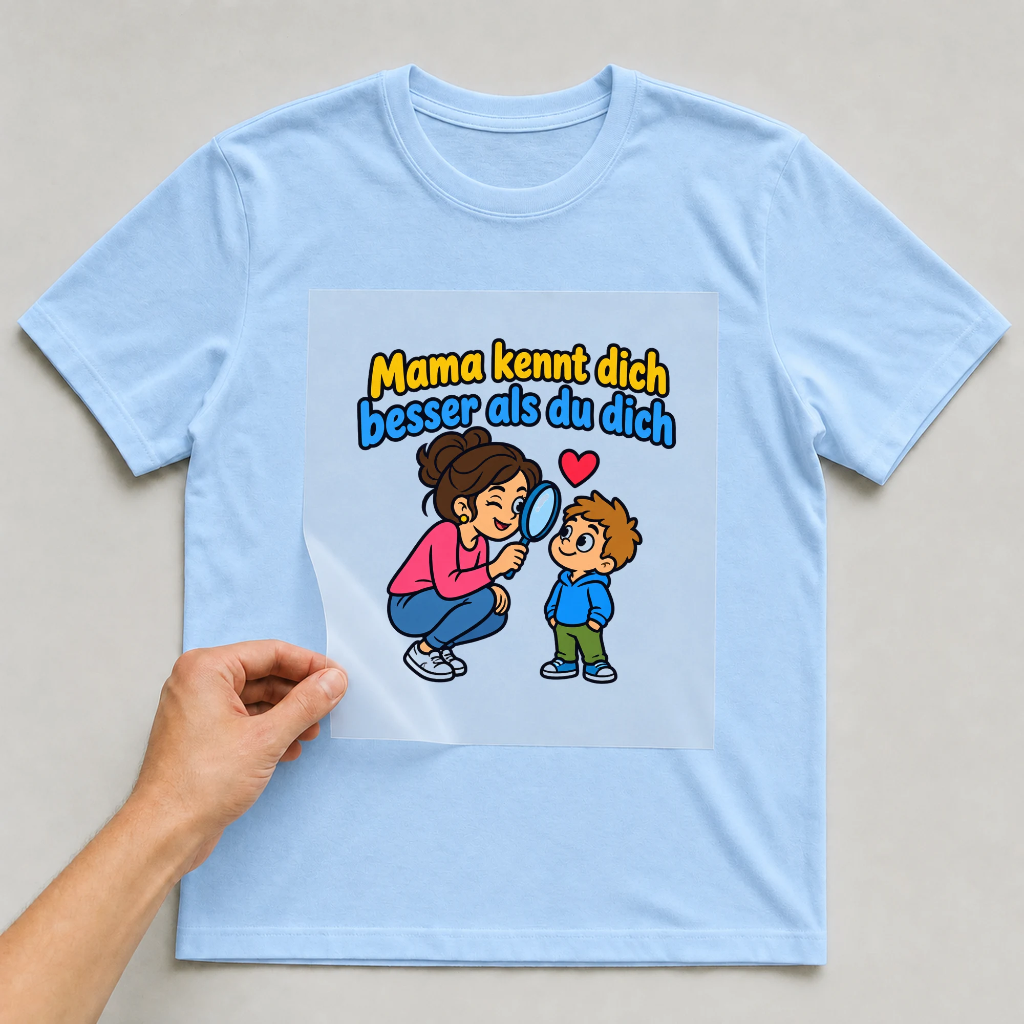 Bügelbild „Mama kennt dich besser als du dich“ auf babyblauem T-Shirt, Folie wird aufgelegt